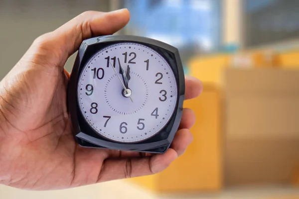 Holding clock on blurred background The time 12:00 am or pm and noon or midnight for made clock isolated or White background Copy space move to clipping path