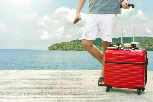 El hombre que tiene equipaje rojo con pasaporte en el fondo de la ciudad desdibujada — Foto de Stock