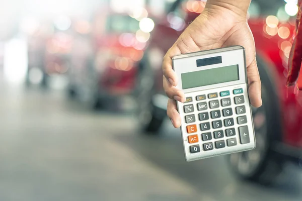 Asiatisk man håller miniräknare för företagsfinansiering på bil showroo — Stockfoto
