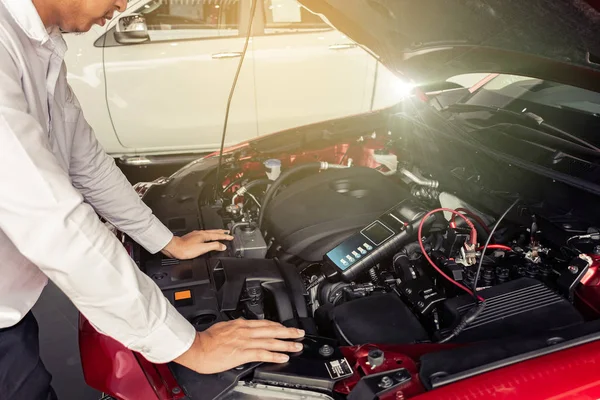 Fabrika taşıma otomotiv otomotiv imajında endüstriyel motor onarımı için Batarya Test Voltmetresi 'ni tutan adam denetimi.