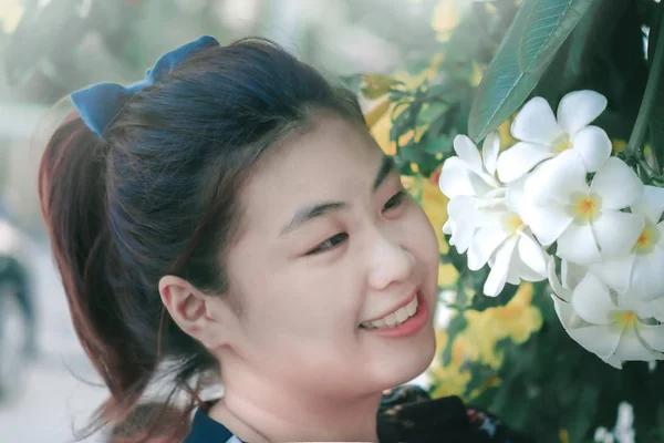 Femme asiatique avec fleur jaune et feuilles vertes ou feuilles floues — Photo