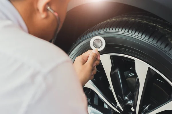 Ázsiai férfi gazdaság sztetoszkóp autó ellenőrzés Gumi gumiabroncsok car.Cl — Stock Fotó