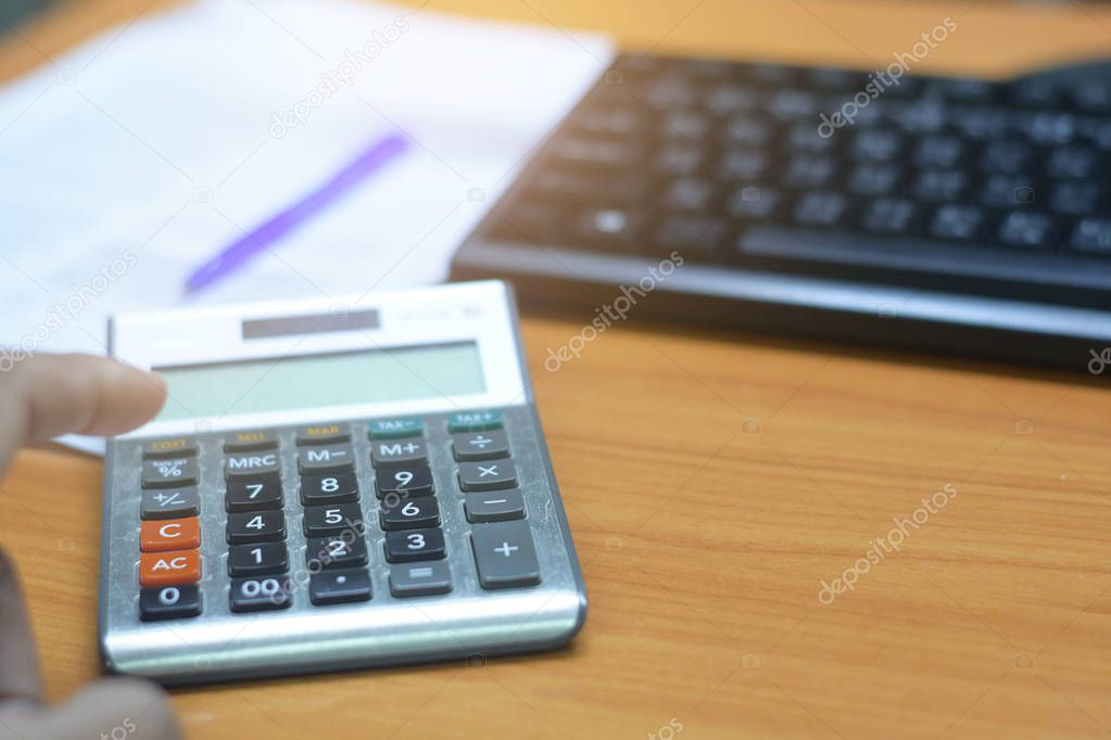 man pressing calculator for business finance on desk office whit