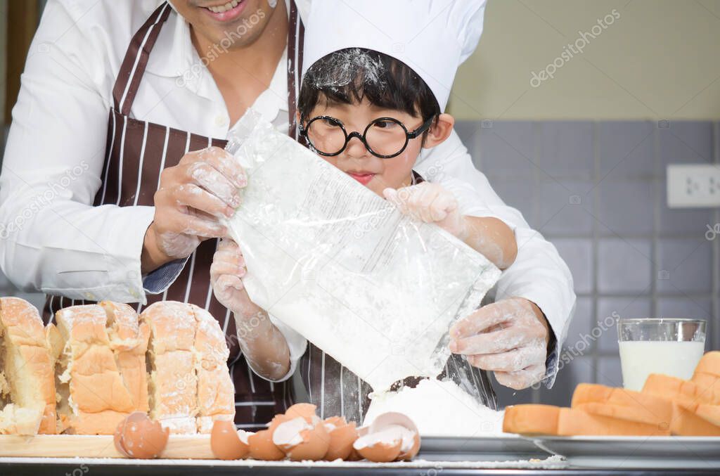 father and the son cooking white flour Kneading bread dough Father teaches children practice baking ingredients bread, egg on tableware in kitchen lifestyle happy Learning life with family Fun to learn