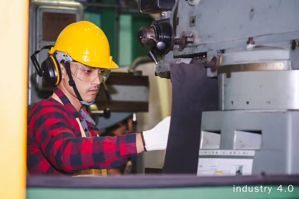 Asian male engineer factory inspection computer control with robot ai machine assist production engineer in industry  wears a helmet male working metalwork control in industrial