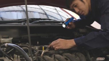 Asyalı adamın görüntülerinde motor arızaları var mı diye kontrol ediliyor. Araba tamir istasyonu ya da teknisyen uzmanı konsepti