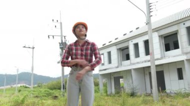 İnşaat alanını kontrol ederken yavaş görüntüler, inşaat alanında dolaşan miğferli Asyalı kadın mühendis. 