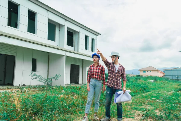 Young asian couple foreman engineering home inspection building house Walk home inspection with looking and pointing construction for check building home on job site to customers with new normol coronavirus covid-19