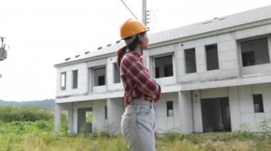 İnşaat alanını kontrol ederken yavaş görüntüler, inşaat alanında dolaşan miğferli Asyalı kadın mühendis. 