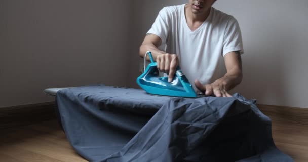Slow footage of ironing a white shirt, close up hands holding the iron, a man sitting and ironing a gray shirt — Stock Footage Slow Footage Ironing White Shirt Close Hands Holding Iron Man Stock Video