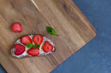 Krem peynirli sandviç ve tahta tahtada taze çilek. Üst Manzara. Düz yatıyordu.