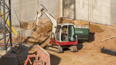 İnşaat alanında çalışan Slav bir adam. Erkek kazıcıyı güvenli bir şekilde kullanmak yerine iş yerinde sigara içiyor..