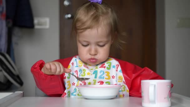 Paffuto bambino mangiare se stessa un porridge sano per la prima volta. Bambina godendo le sue colazioni . — Video Stock