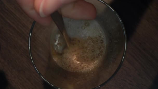 从上往下看茶匙是如何在杯子里搅拌冷咖啡的。女人每天早上用牛奶自己煮美味的咖啡. — 图库视频影像