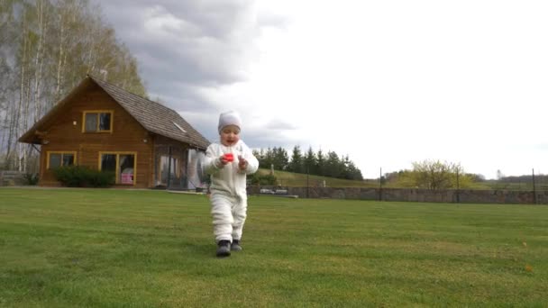 Happy toddler girl cammina nel cortile. Ragazzina sorridente gioca con i giocattoli. Bambino che cammina con vestiti caldi. — Video Stock