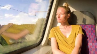 Kafkas görünümlü kadın tren penceresinden manzaraya hayran. Tatlı yüzlü kadın tatilinin tadını çıkarıyor. Sarı saç, doğal yüz, çiller, saç topuzu..