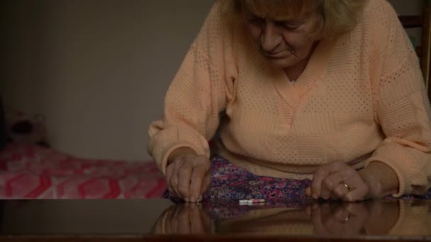 Staruszka patrzy na tabletki i stara się znaleźć właściwą. Babcia z blond włosami, zmarszczkami i obrączką. — Wideo stockowe