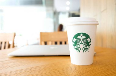 Bangkok, Tayland - 15 Haziran 2018: Beyaz kahve fincanı ile Starbucks logosu ve ormanlık masa üstünde laptop