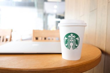 Bangkok, Tayland - 15 Haziran 2018: Beyaz kahve fincanı ile Starbucks logosu ve ormanlık masa üstünde laptop
