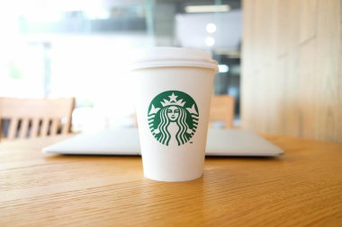 Bangkok, Tayland - 15 Haziran 2018: Beyaz kahve fincanı ile Starbucks logosu ve ormanlık masa üstünde laptop