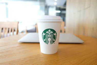 Bangkok, Tayland - 15 Haziran 2018: Beyaz kahve fincanı ile Starbucks logosu ve ormanlık masa üstünde laptop
