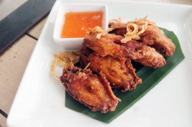 Ahşap masa üzerinde beyaz plaka soslu kızarmış tavuk kanadı