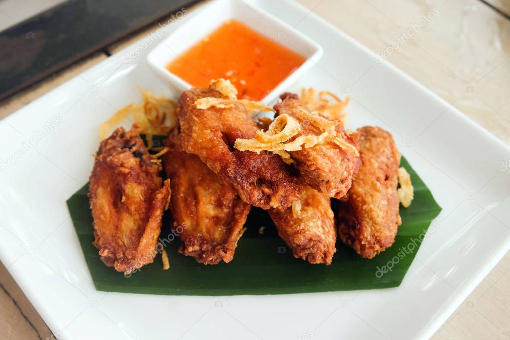 Fried chicken wings with sauce in white plate on wooden table