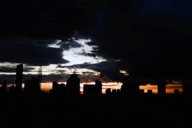 Bulutlar günbatımı ile şehrin üzerinde sk