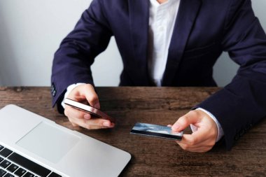 Kredi kartı tutan ve online alışveriş için akıllı telefon kullanarak online ödeme Mans eller