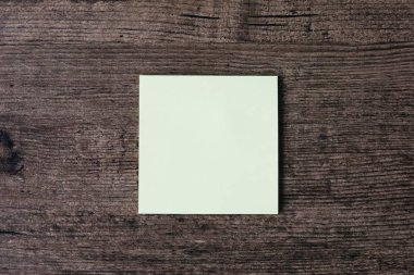 Ahşap masa boş bir yapışkan not kağıdına görüntüsünü üstten görünüm