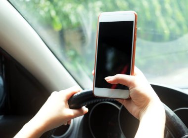 Bir araba sürüş sırasında akıllı telefon kullanan kadın