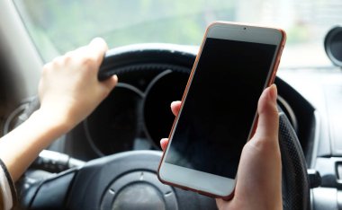 Bir araba sürüş sırasında akıllı telefon kullanan kadın