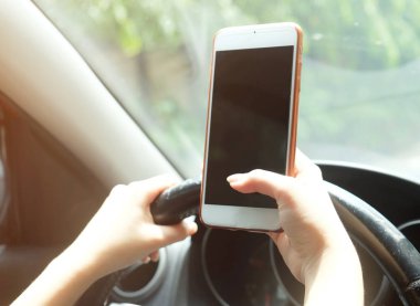 Bir araba sürüş sırasında akıllı telefon kullanan kadın