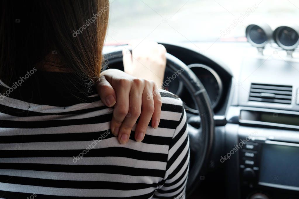 Close up woman having pain on neck and shoulder while driving car. Long driving on the way