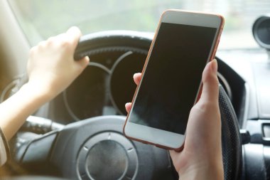 Bir araba sürüş sırasında akıllı telefon kullanan kadın