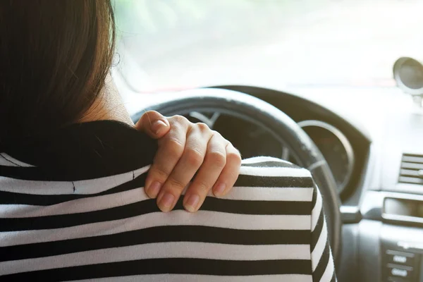 Close up woman having pain on neck and shoulder while driving car. Long driving on the way