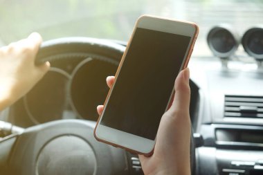 Bir araba sürüş sırasında akıllı telefon kullanan kadın