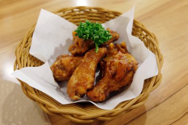 Kızarmış tavuk kanatları beyaz plaka üzerinde ahşap masa