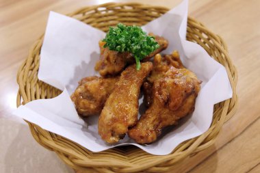 Kızarmış tavuk kanatları beyaz plaka üzerinde ahşap masa