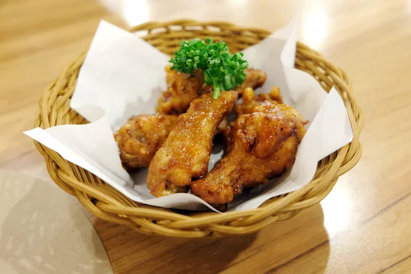 Kızarmış tavuk kanatları beyaz plaka üzerinde ahşap masa