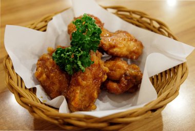 Kızarmış tavuk kanatları beyaz plaka üzerinde ahşap masa