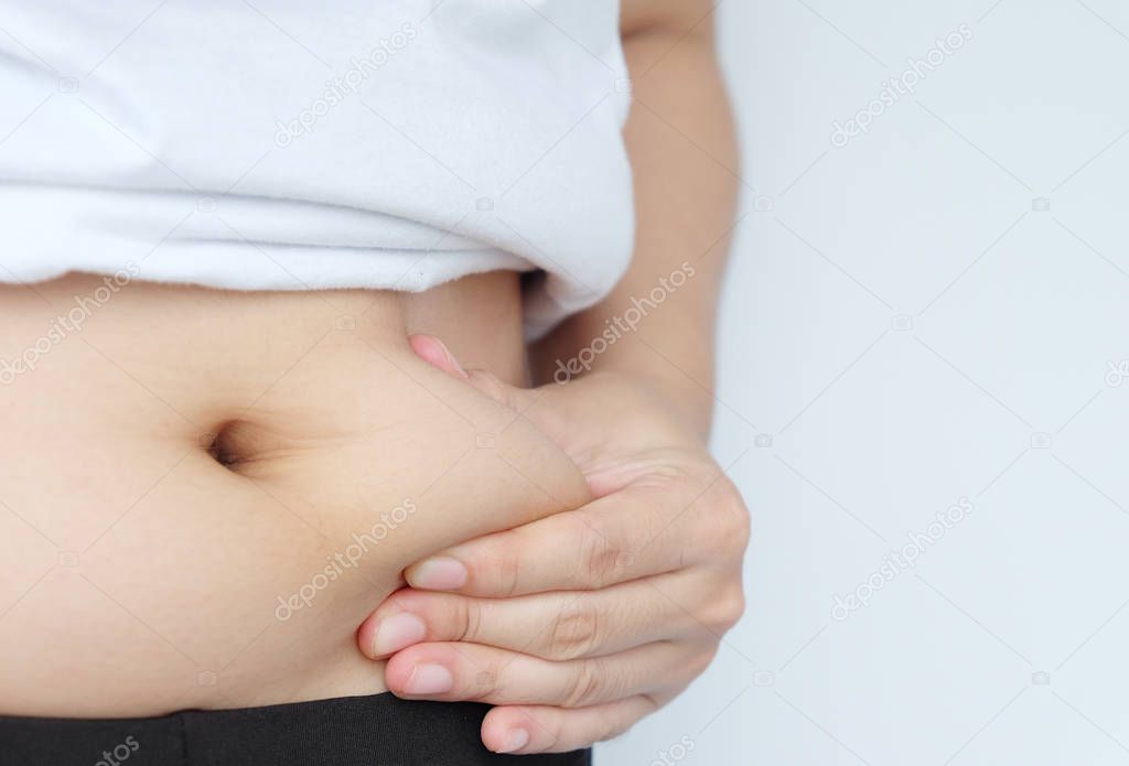 Side of woman hand catching fat body belly paunch , diabetic risk factor