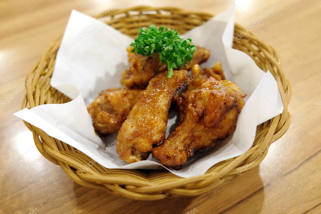 Fried chicken wings in white plate on wooden table