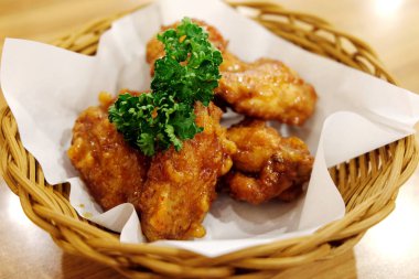 Kızarmış tavuk kanatları beyaz plaka üzerinde ahşap masa