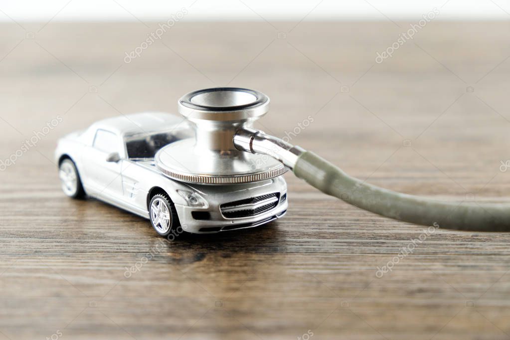 Stethoscope checking up the car on wooden table, Concept of car check up, repair and maintenance