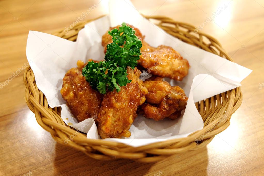 Fried chicken wings in white plate on wooden table