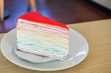 Ahşap masa üzerinde beyaz tabakta gökkuşağı krep pasta