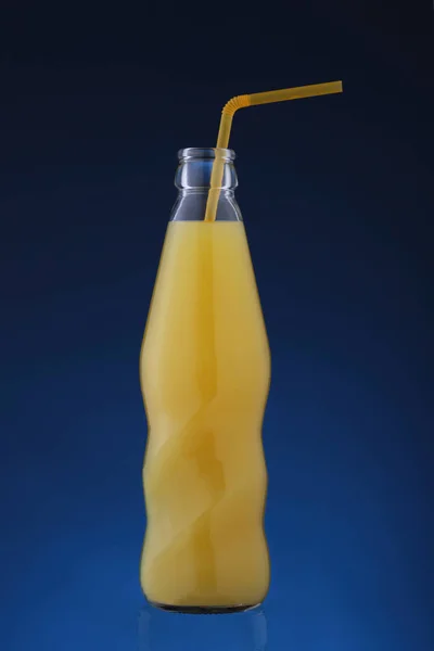 Flasche mit Orangensaft auf blauem Hintergrund — Stockfoto