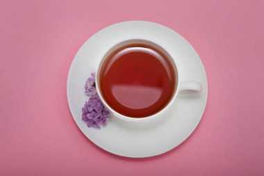 Pembe arka planda taze leylak çiçekleri ile çay fincan