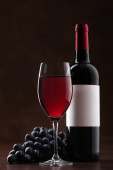 Láhev červeného vína se štítkem se skleněnými a zralými hrozny